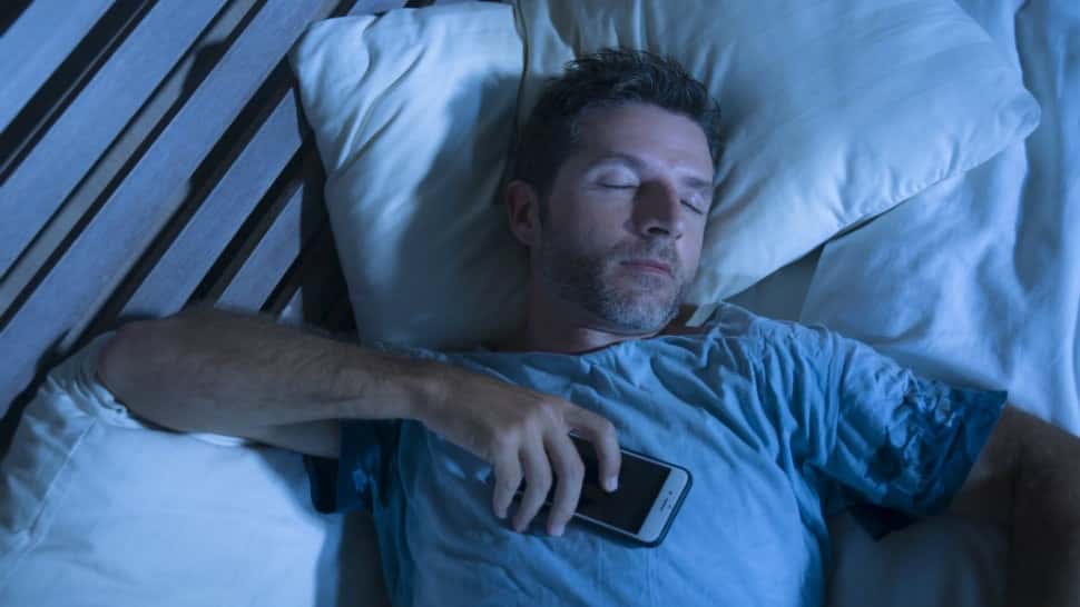 صورة لـ كيفية النوم بشكل أفضل مع إعدادات iPhone وبعض التعديلات | man-sleeping-smartphone-min-DzTechs