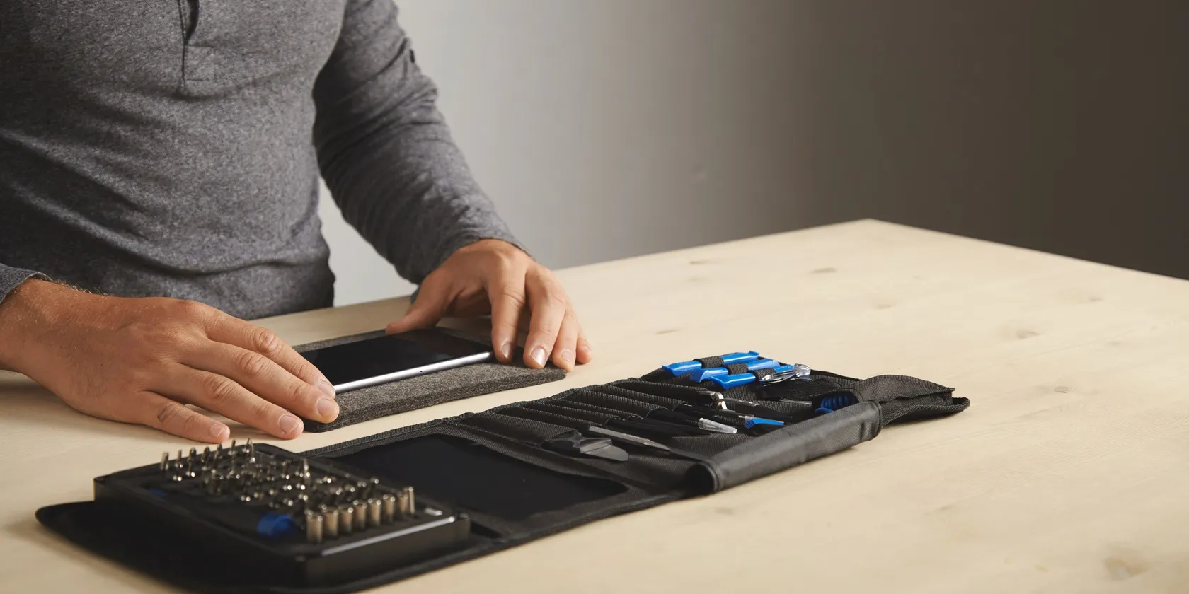 رجل يستعد لإصلاح هاتف ذكي باستخدام طقم إصلاح الهواتف الخاص به