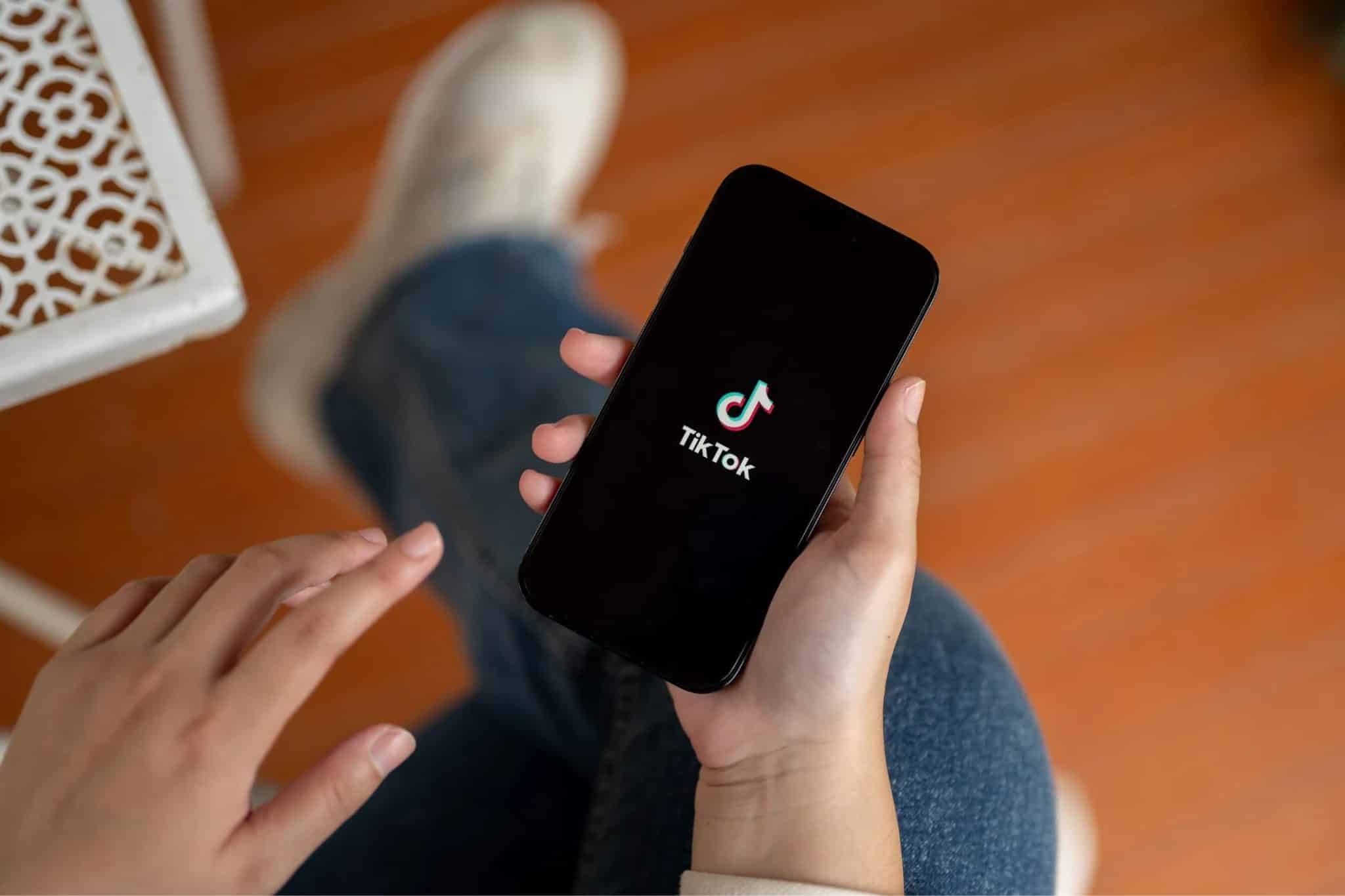 شخص يحمل هاتفًا ذكيًا عليه تطبيق TikTok