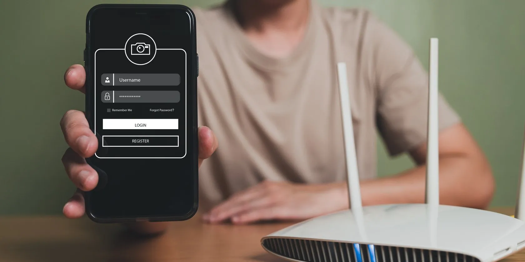 Man holding mobile phone next to router