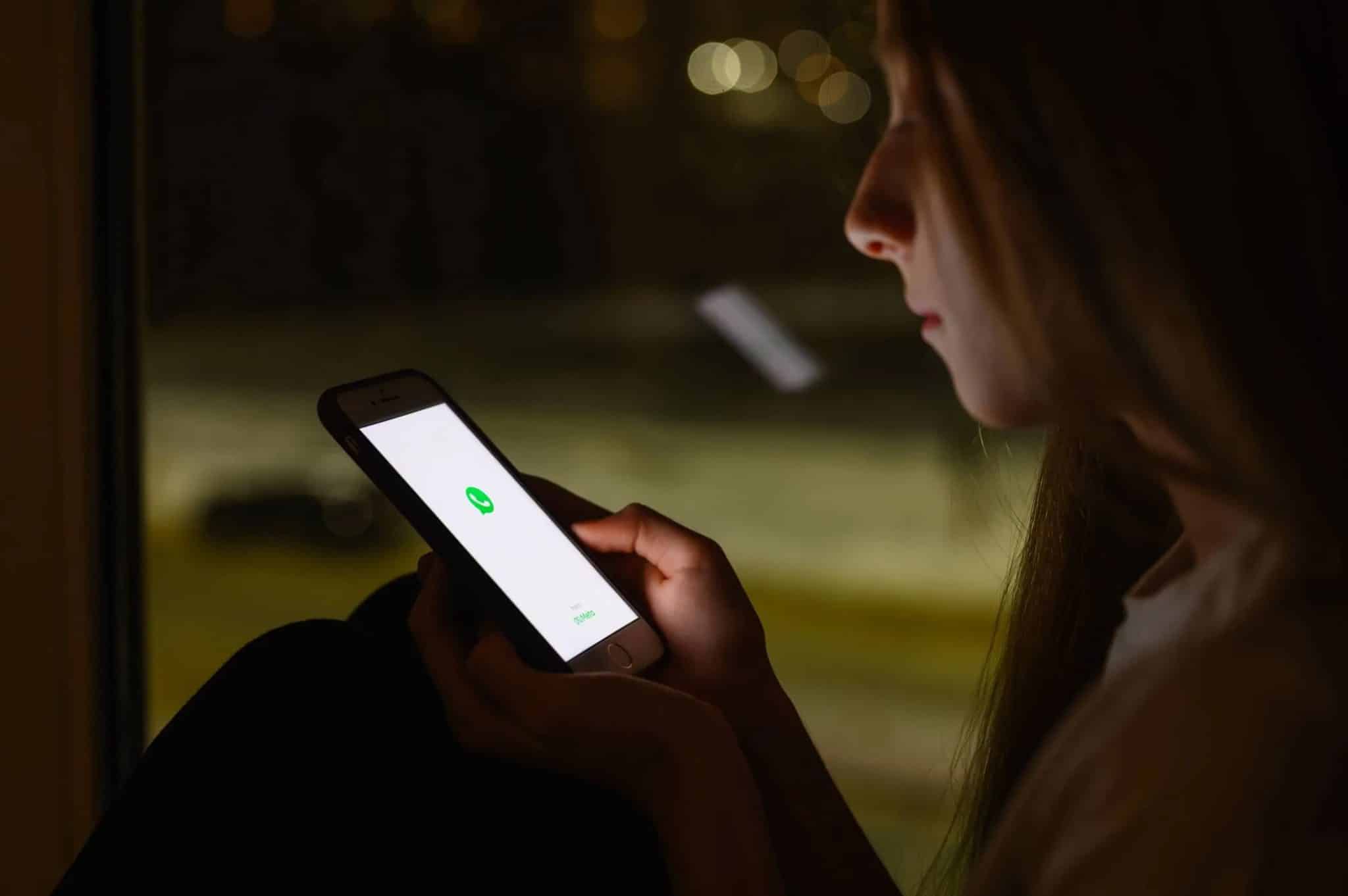 امرأة تستخدم هاتف iPhone في الليل مع صورة ساطعة على الشاشة