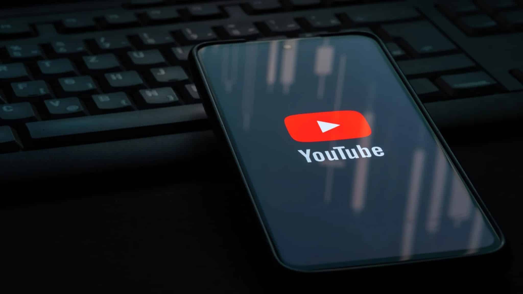 شعار يوتيوب على هاتف ذكي يستند على لوحة مفاتيح