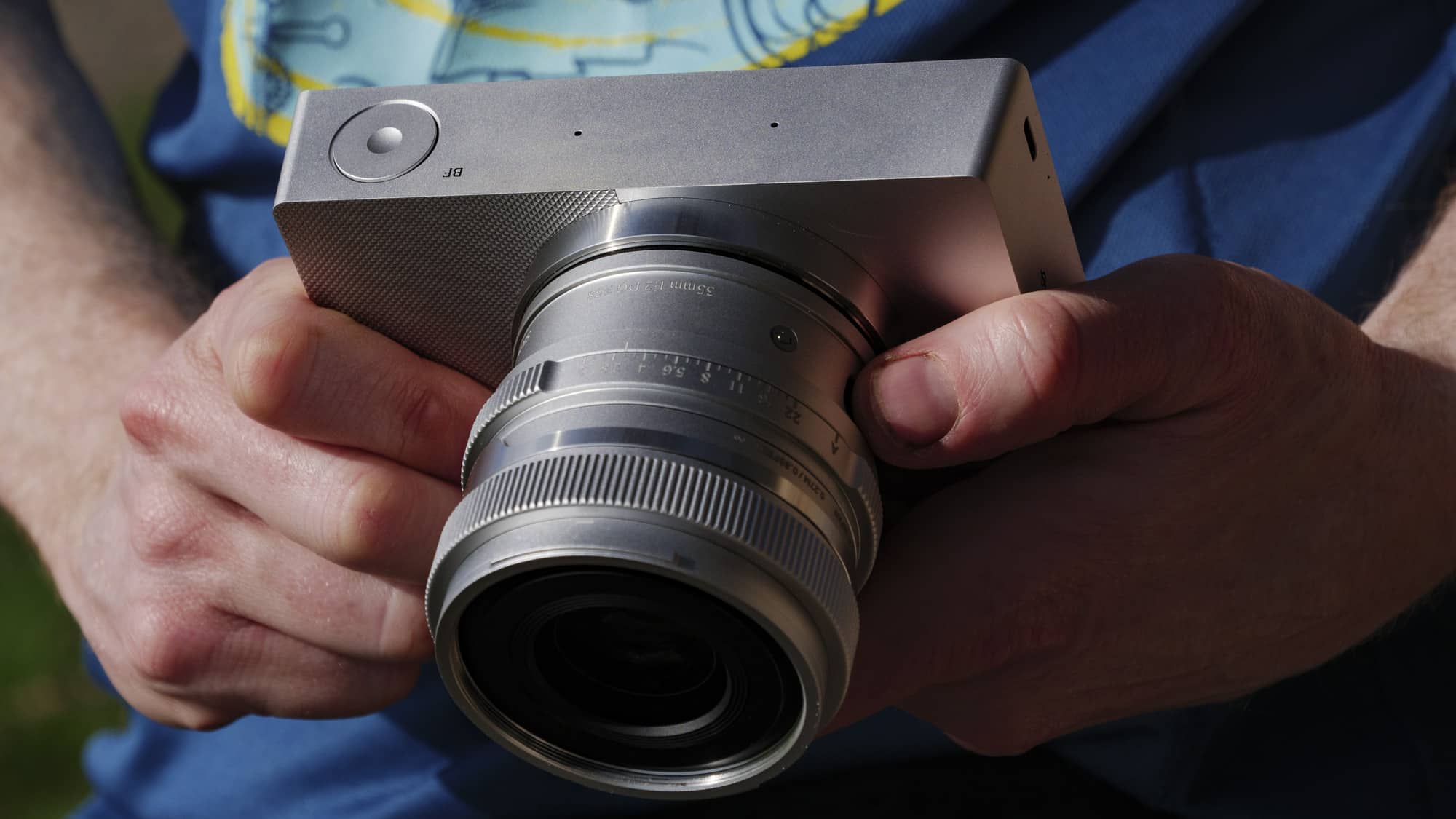 كاميرا Sigma BF فضية مع عدسة 35mm f/2 DG معاصرة متصلة، في اليد