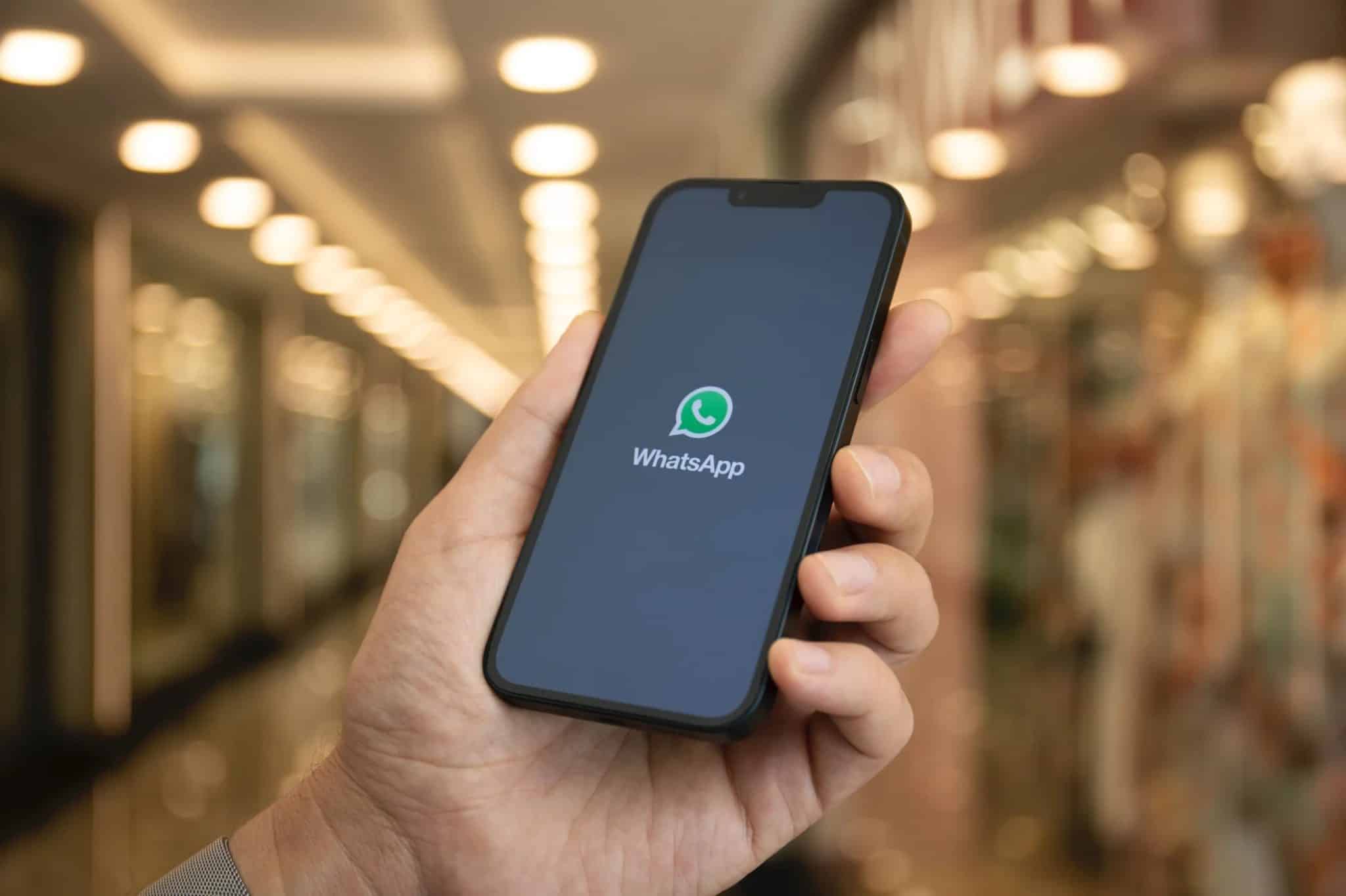 يد تحمل هاتفًا ذكيًا بشعار WhatsApp