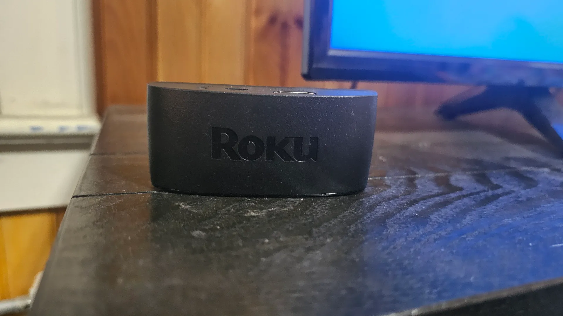جهاز Roku للبث مثبت على طاولة تلفزيون بجوار جهاز تلفزيون.