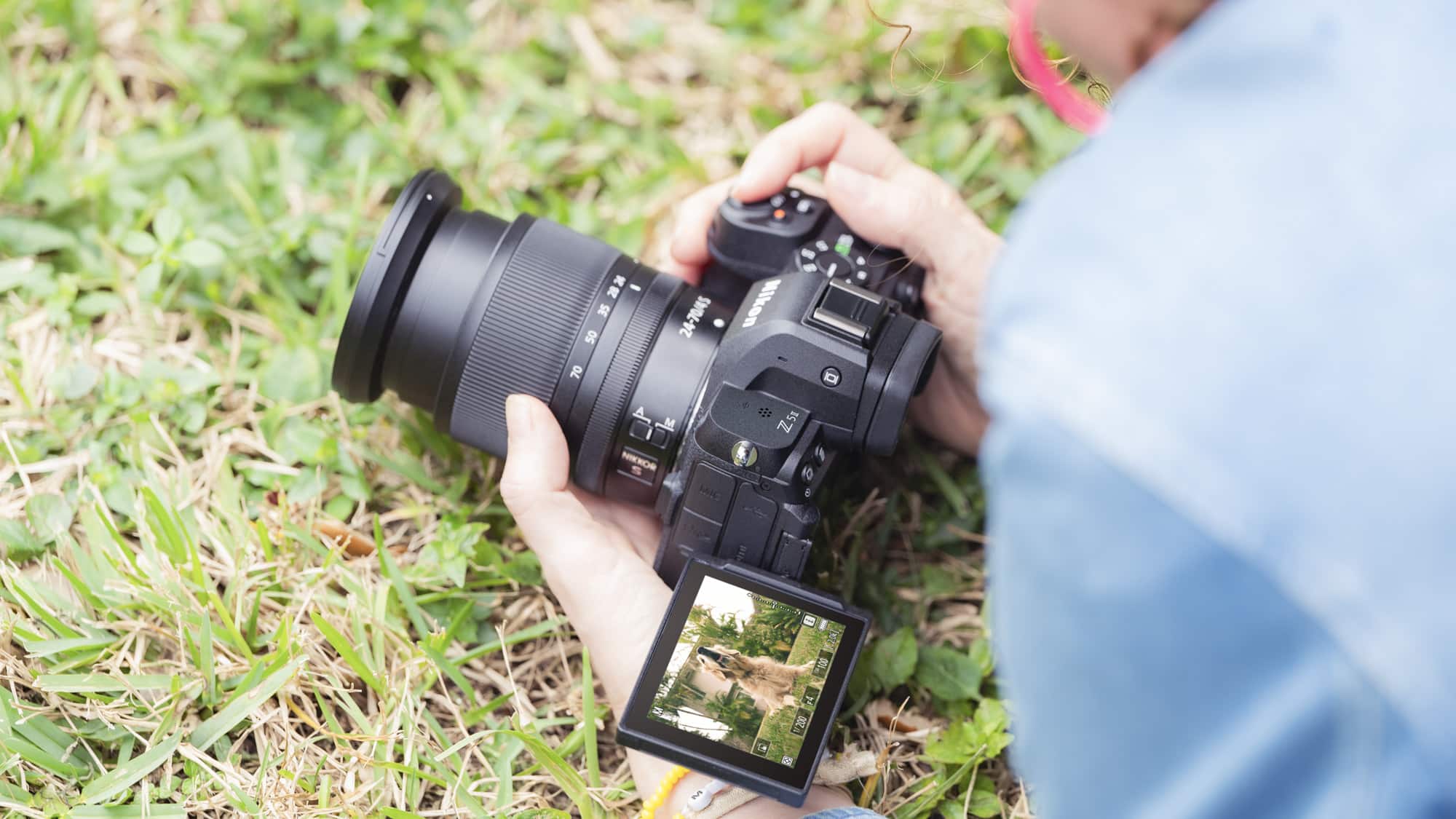 كاميرا Nikon Z5 II في اليد على مستوى الأرض، شاشة اللمس مفتوحة ومائلة لأعلى