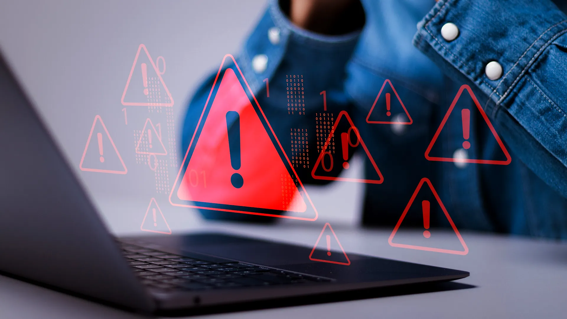 اختراق بيانات على جهاز كمبيوتر محمول مع مثلثات حمراء تحذيرية