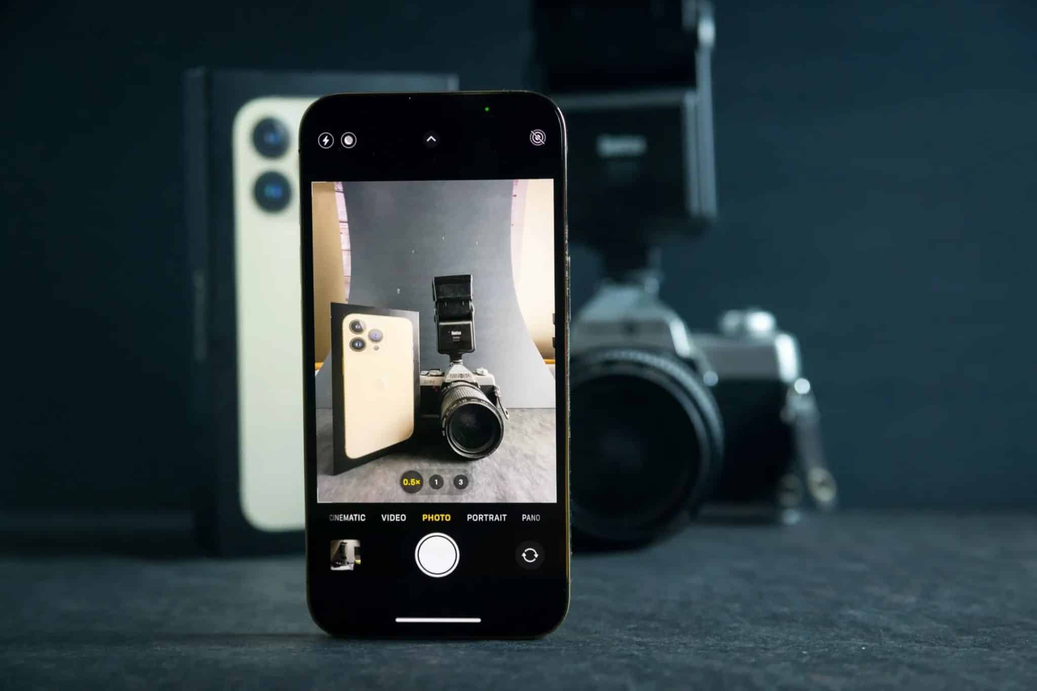 Photo of brand new Iphone 13 with camera app taking photo of mirror less camera and Iphone 13 official box.