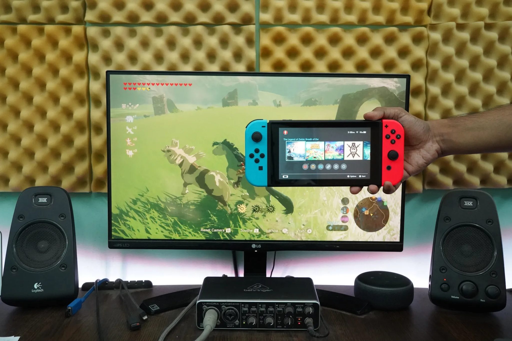 رجل يحمل جهاز Nintendo Switch أمام شاشة كمبيوتر