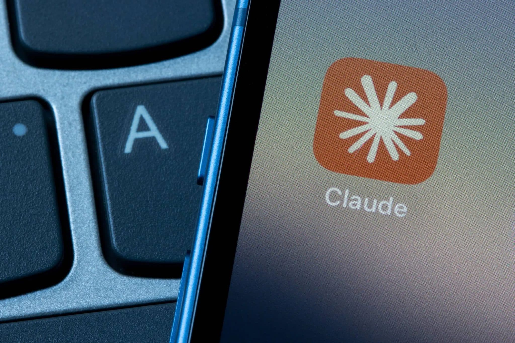 أيقونة تطبيق Claude على هاتف ذكي بجوار لوحة مفاتيح الكمبيوتر المحمول