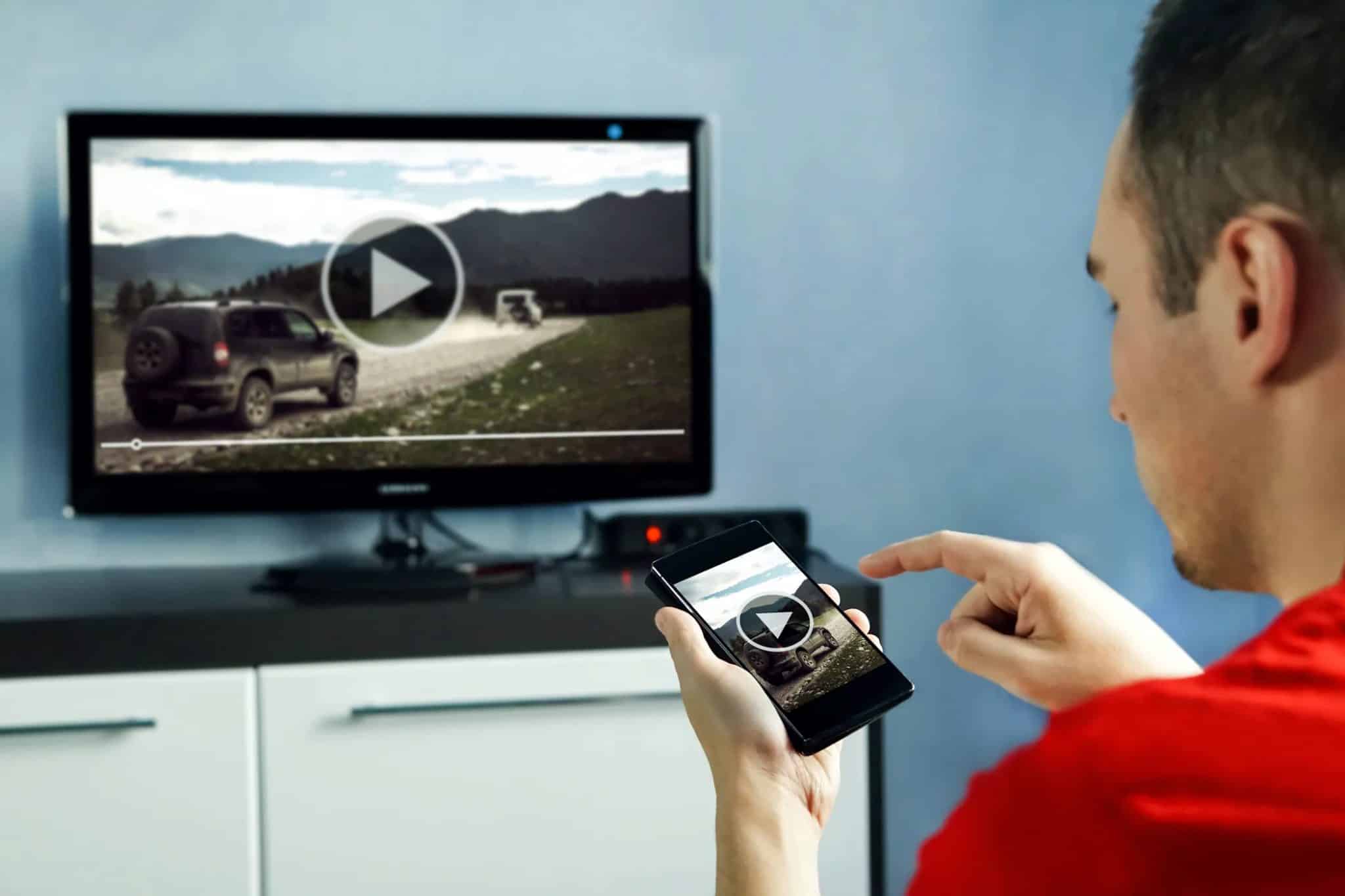 رجل يشاهد فيديو على تلفاز ذكي وتطبيق مصاحب.