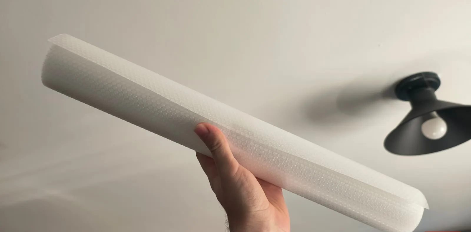 يد تحمل لفة بطانة بلاستيكية