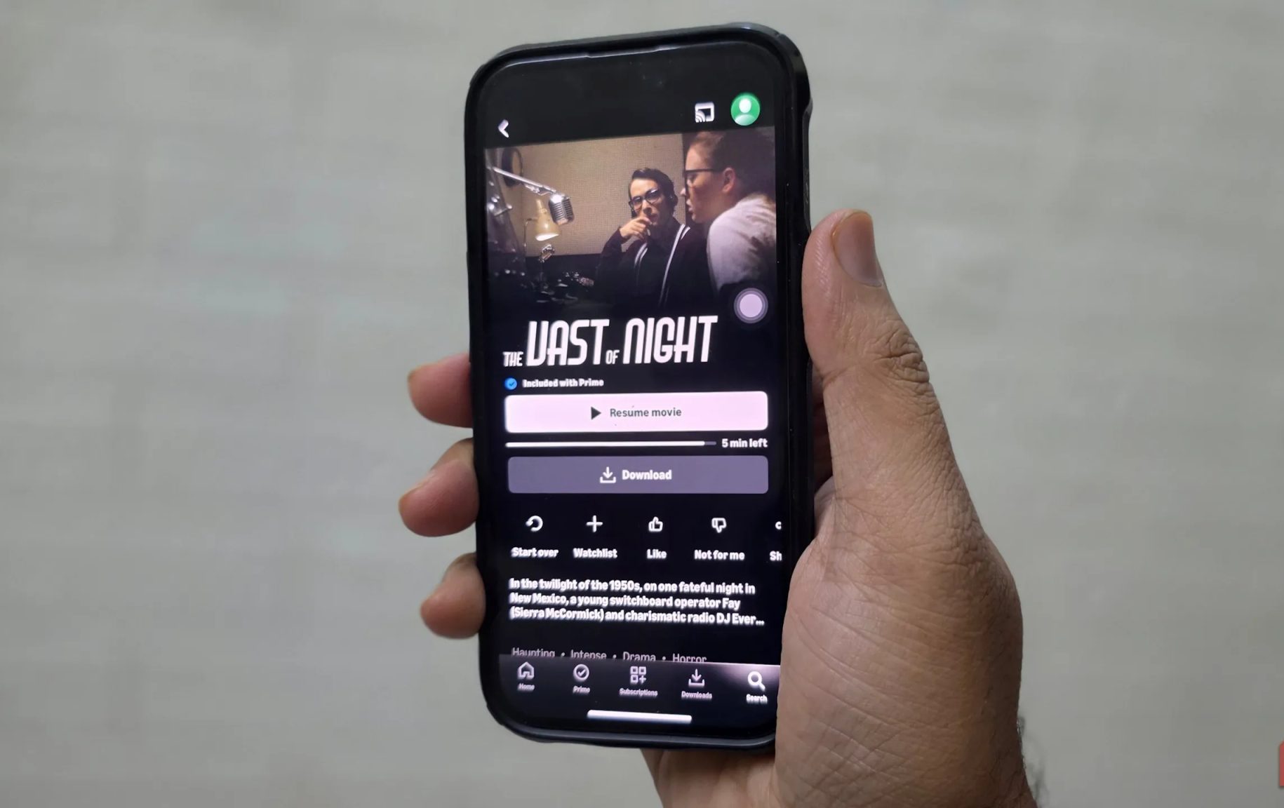 رجل يحمل iPhone ويشاهد فيلم The Vast of Night على Prime Video.