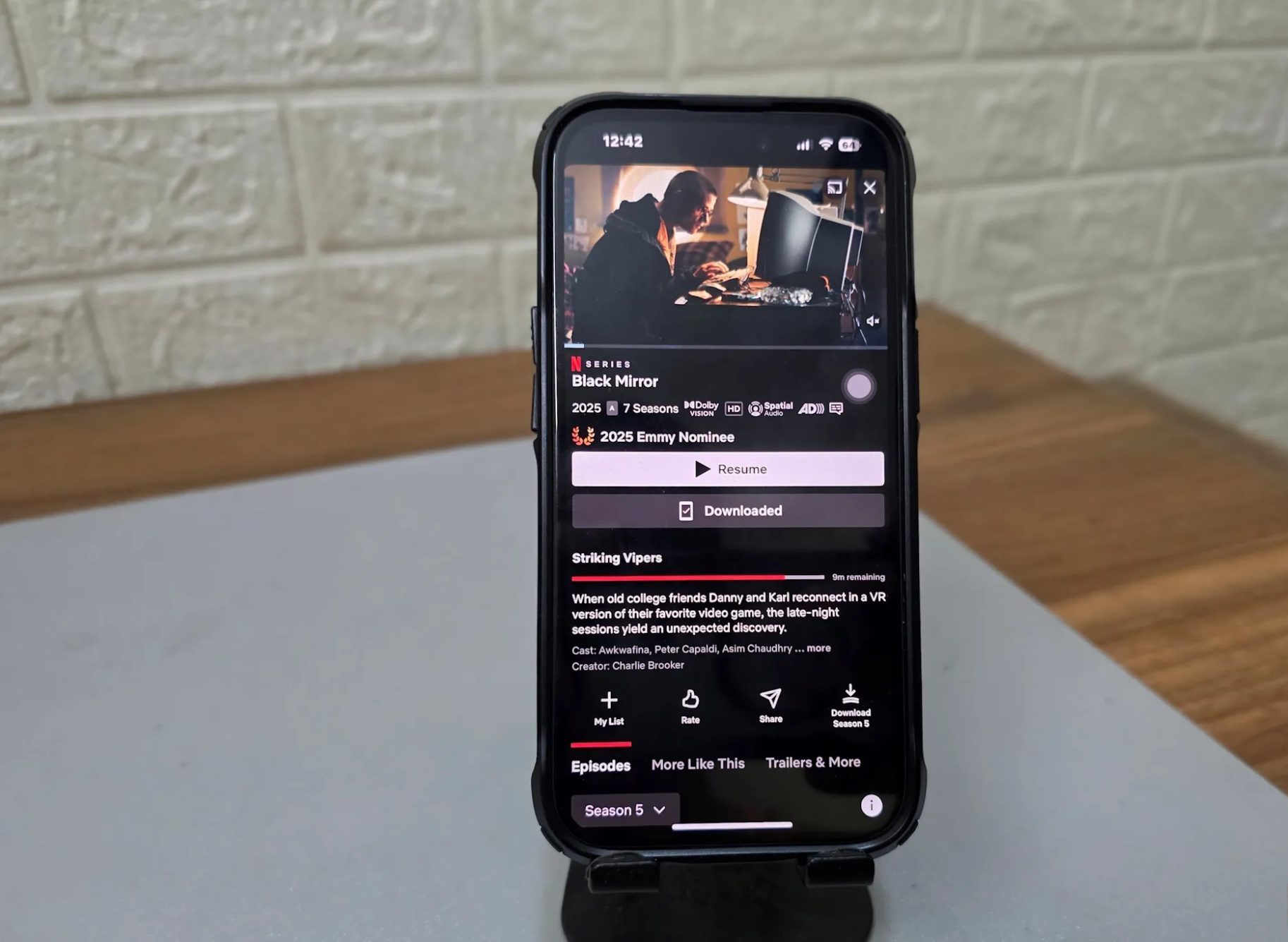 A phone holder holds an iPhone with Netflix open