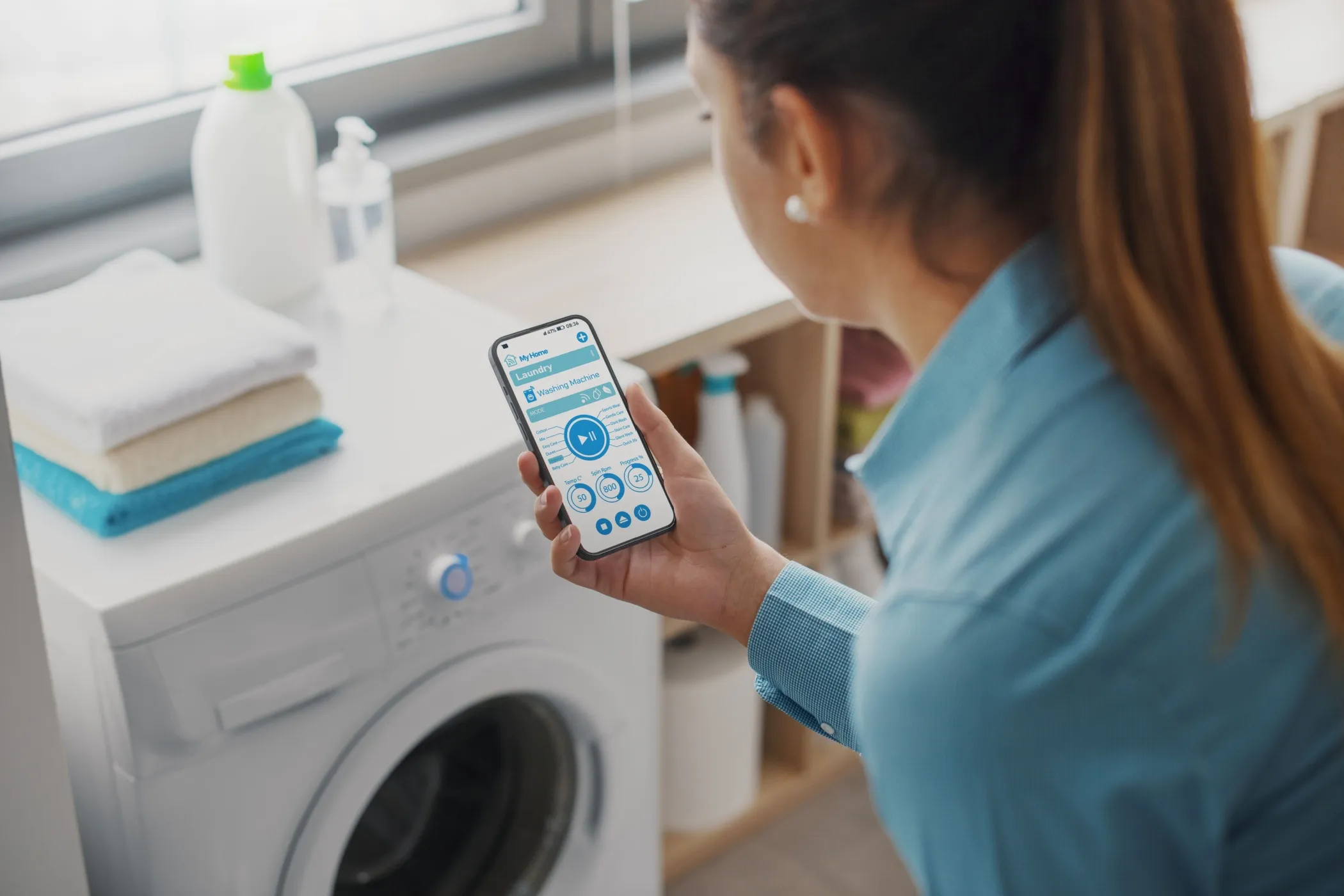 a woman using a smartphone with a washing machine