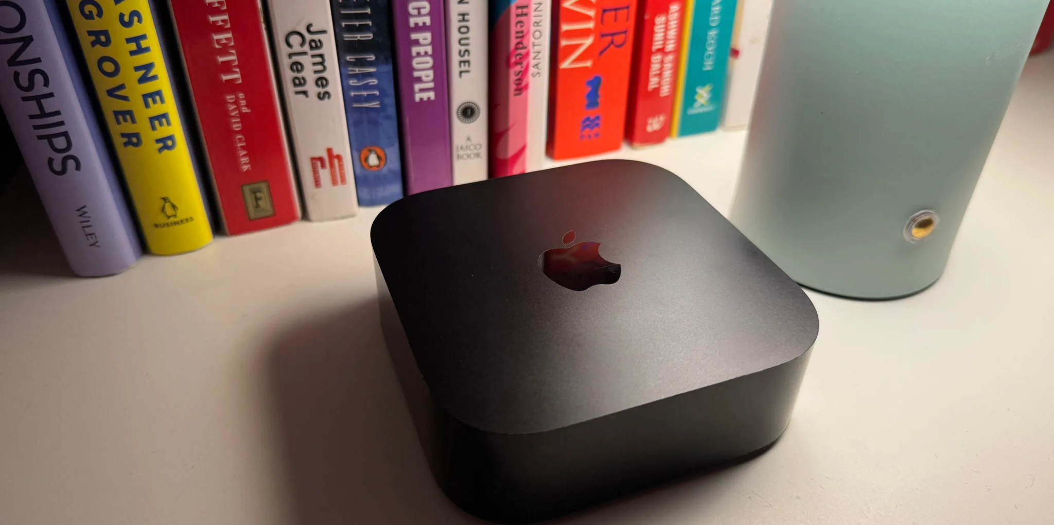جهاز Apple TV مع بعض الكتب في الخلفية