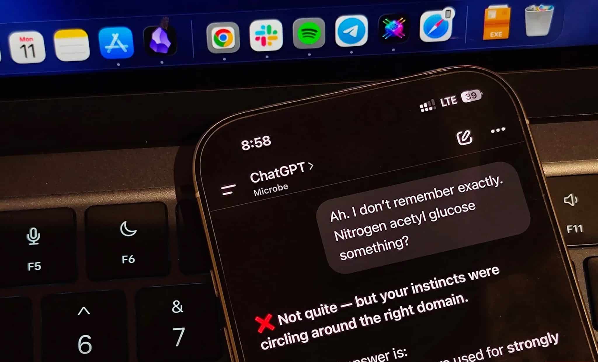 ChatGPT على جهاز iPhone بجانب لوحة مفاتيح كمبيوتر محمول