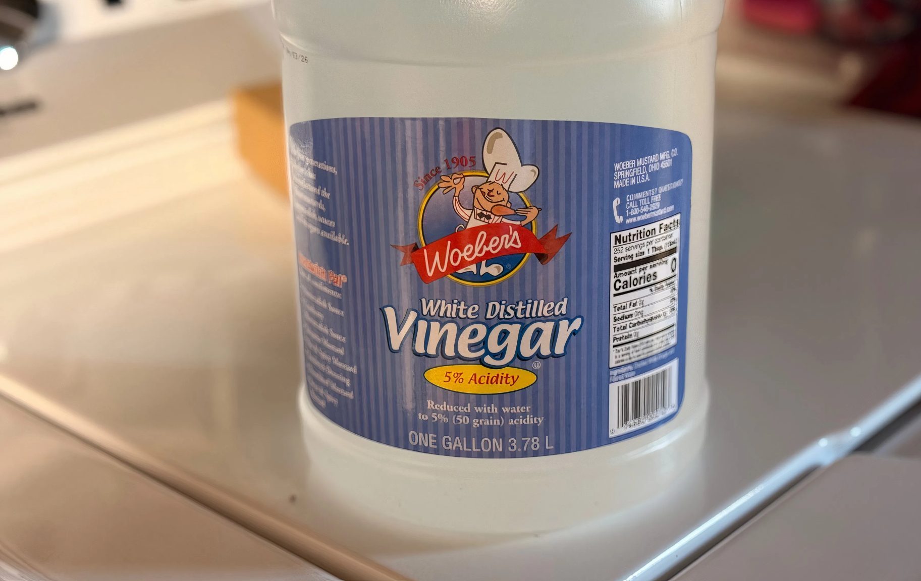 A bottle of vinegar sitting on the top of a washing machine.