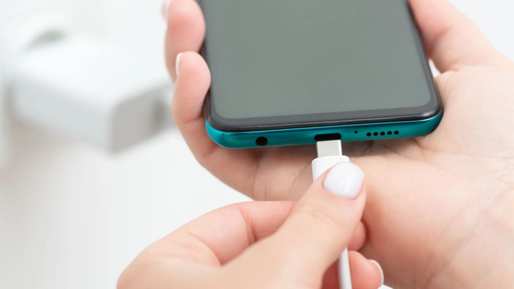 يد تقوم بتوصيل شاحن بهاتف ذكي