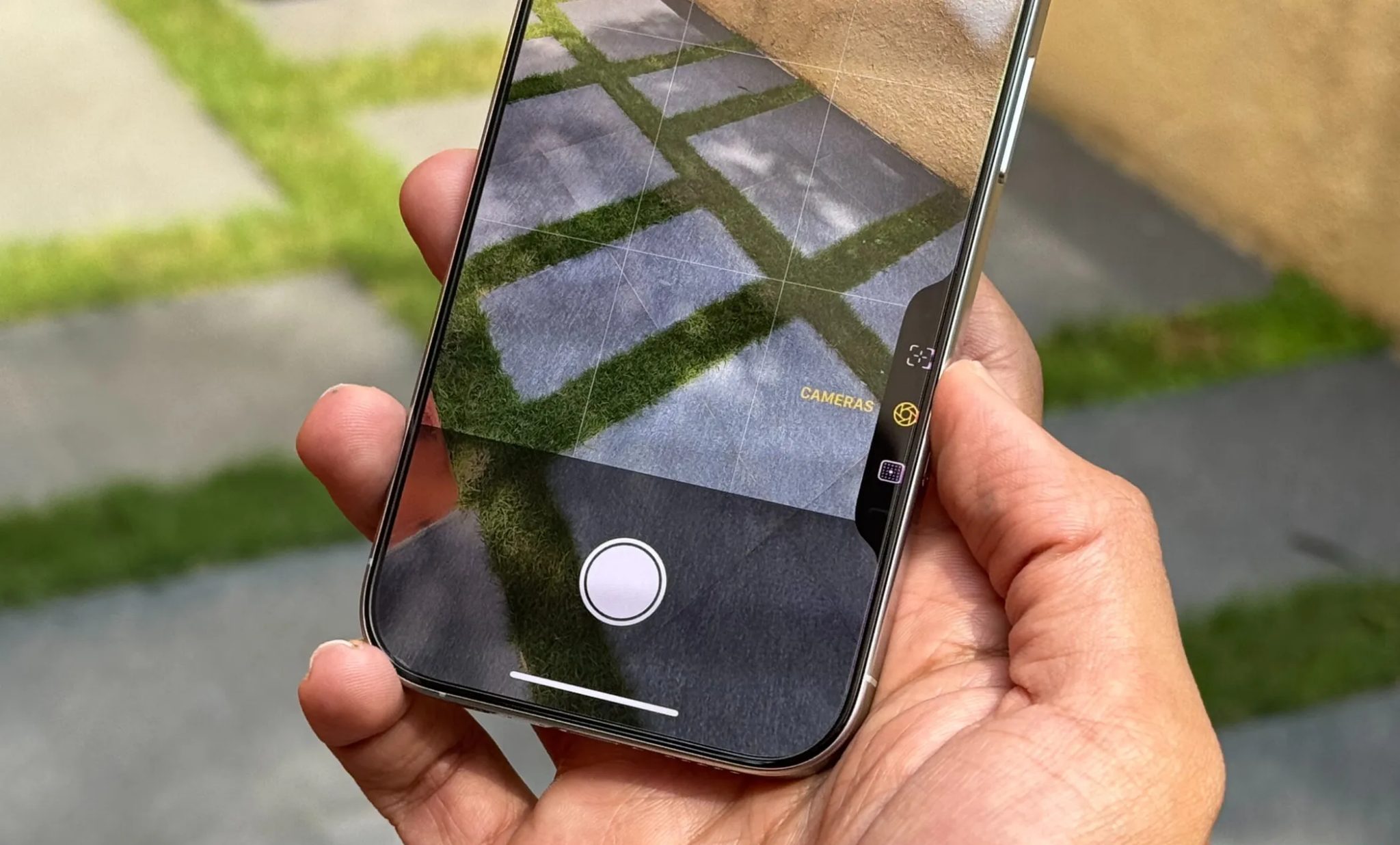 iPhone 16 Pro في يد رجل يعرض واجهة مستخدم التحكم في الكاميرا في تطبيق الكاميرا