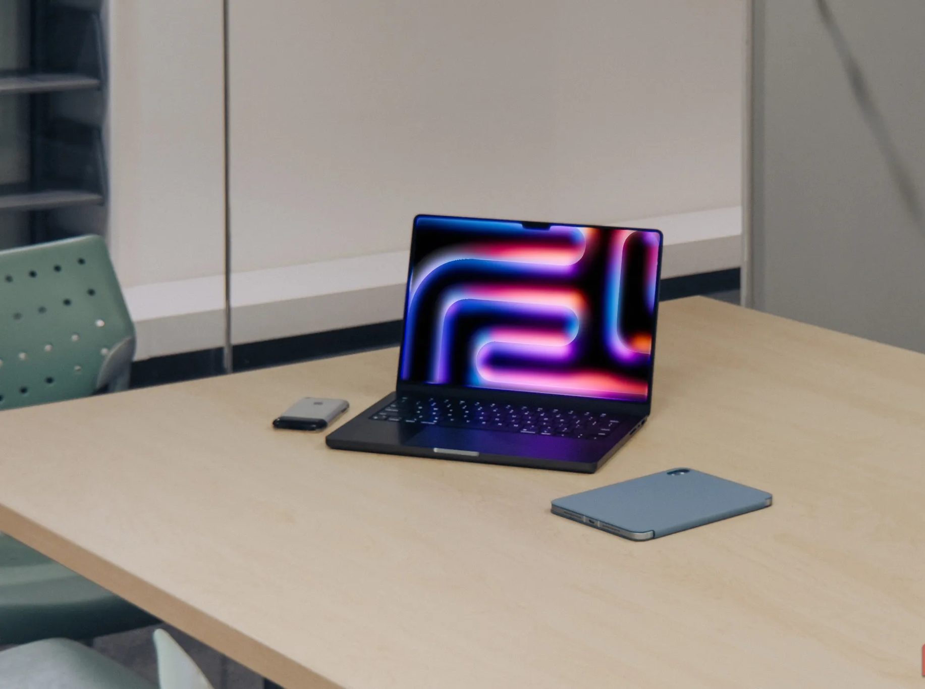 M4 MacBook Pro next to iPad and iPhone 2G on wooden table