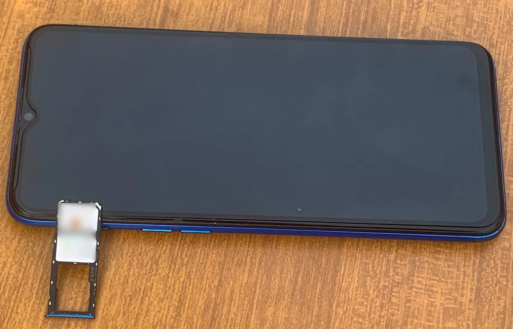 هاتف Android موضوع على طاولة مع إزالة فتحات بطاقة SIM وبطاقة الذاكرة منه.