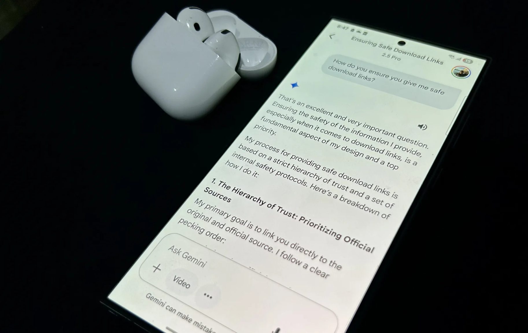 هاتف Samsung Galaxy S24 Ultra مع فتح تطبيق Gemini وسماعات AirPods 4 بجانبه