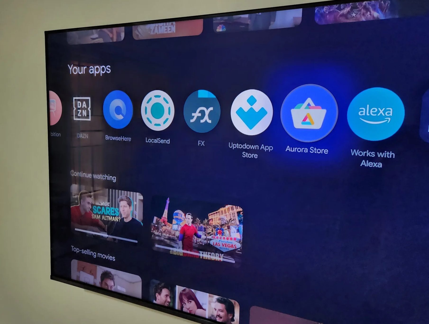 تلفزيون TCL Google TV معروض على الحائط يعرض التطبيقات على الشاشة الرئيسية