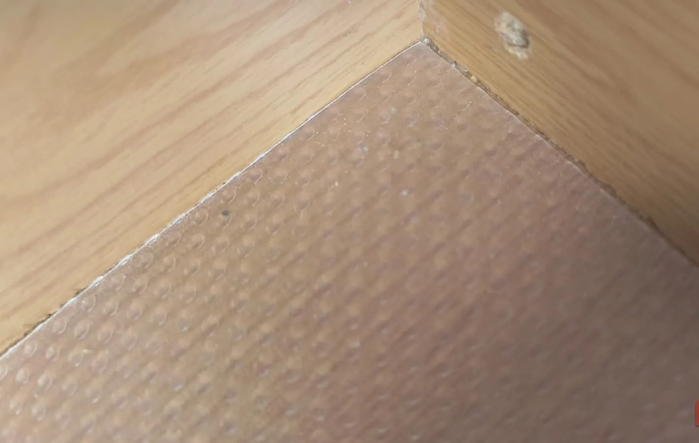 The corner of a drawer with plastic liner in the bottom