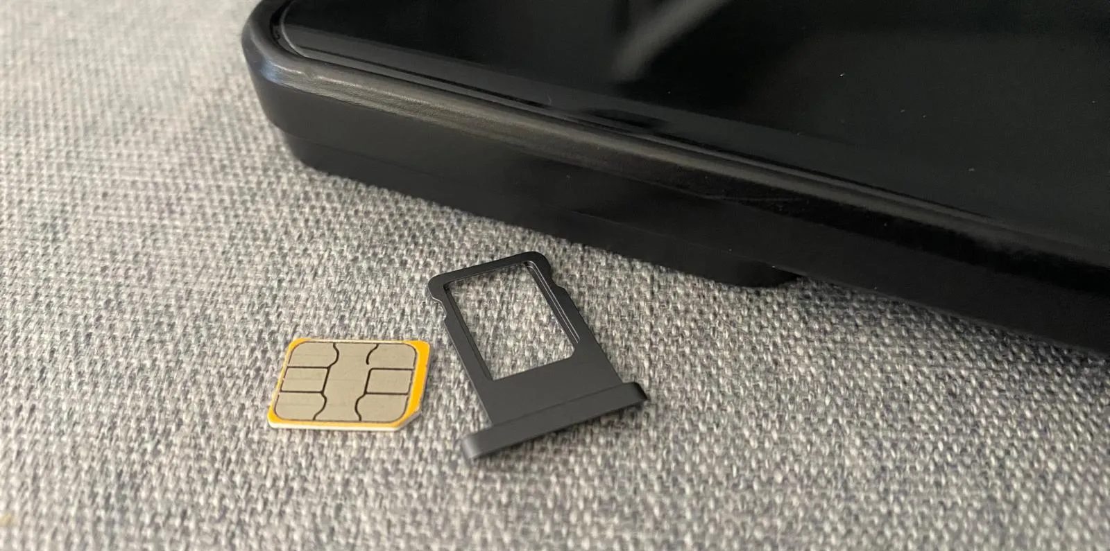 شريحة SIM وحامل بلاستيكي بجوار هاتف خلوي على طاولة