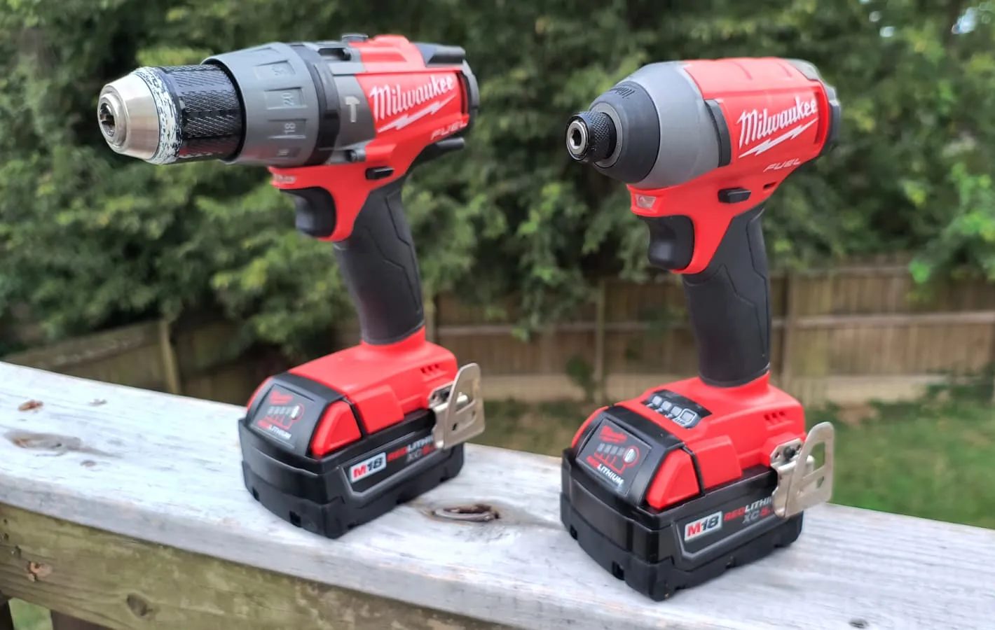 A cordless drill and driver on a wooden rail