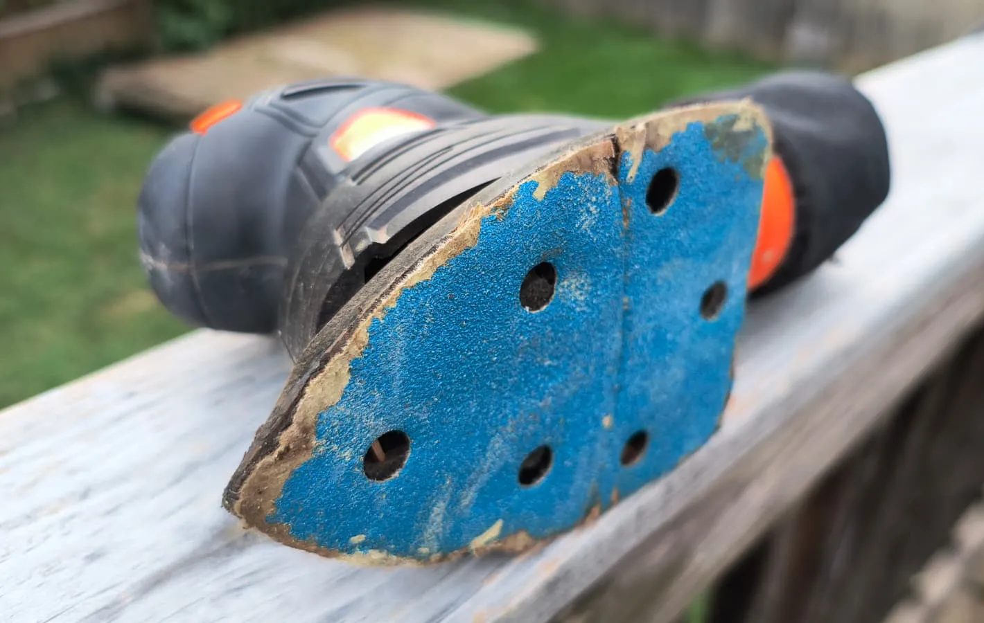 The bottom of a small electric sander on a wooden rail