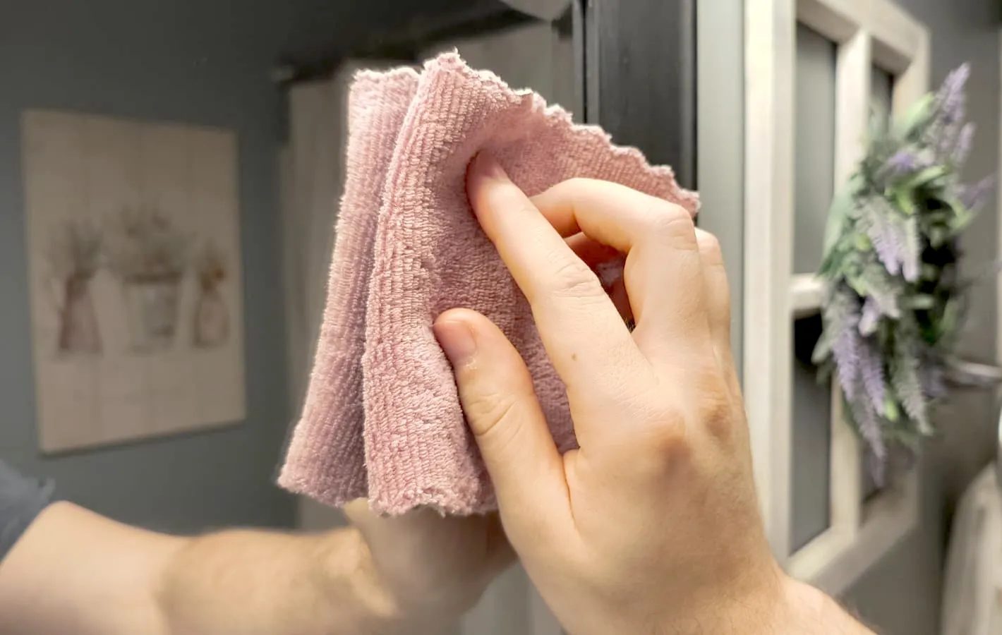 يد تستخدم قطعة قماش من الألياف الدقيقة لتنظيف مرآة
