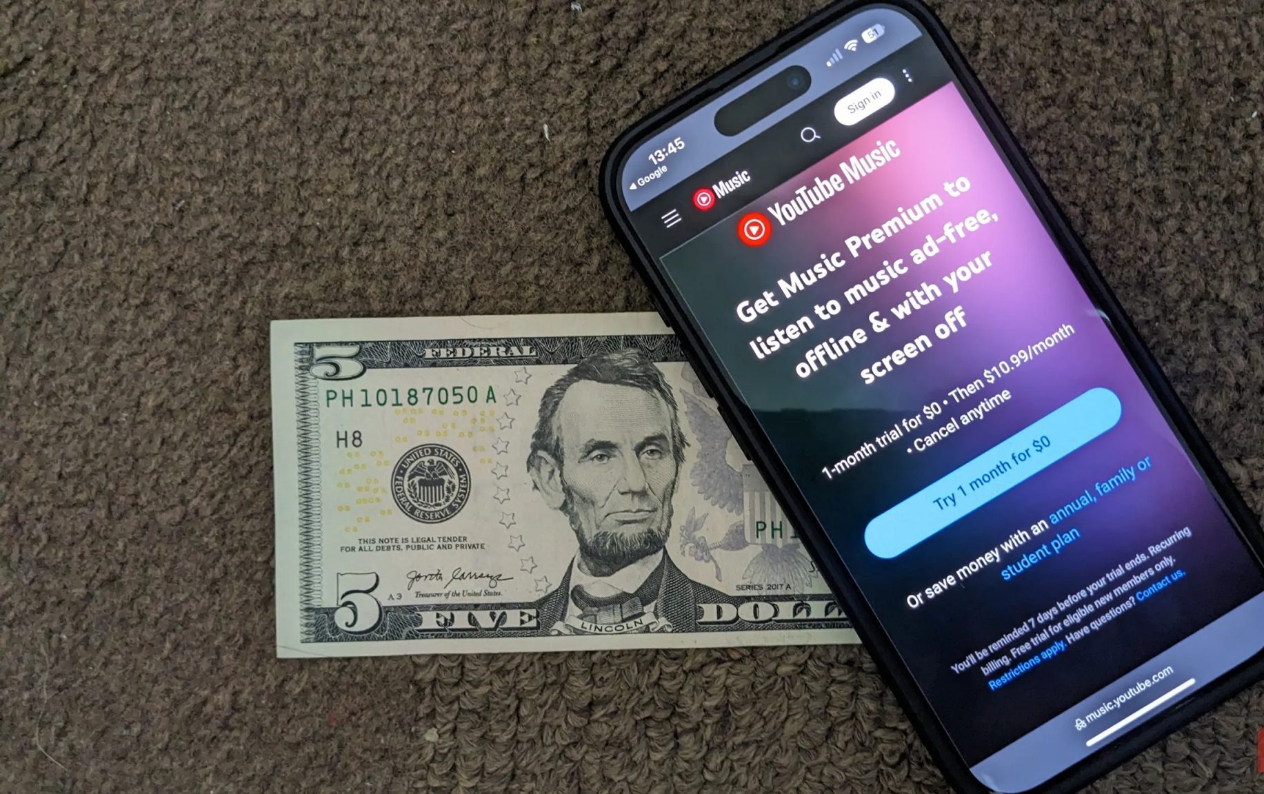صفحة الاشتراك في YouTube Music مع وضع ورقة نقدية أمريكية بقيمة خمسة دولارات تحتها