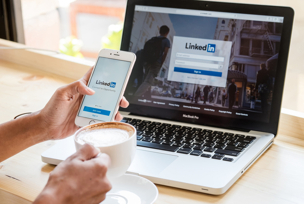 شخص يسجل الدخول إلى LinkedIn على هاتفه وجهاز الكمبيوتر المحمول
