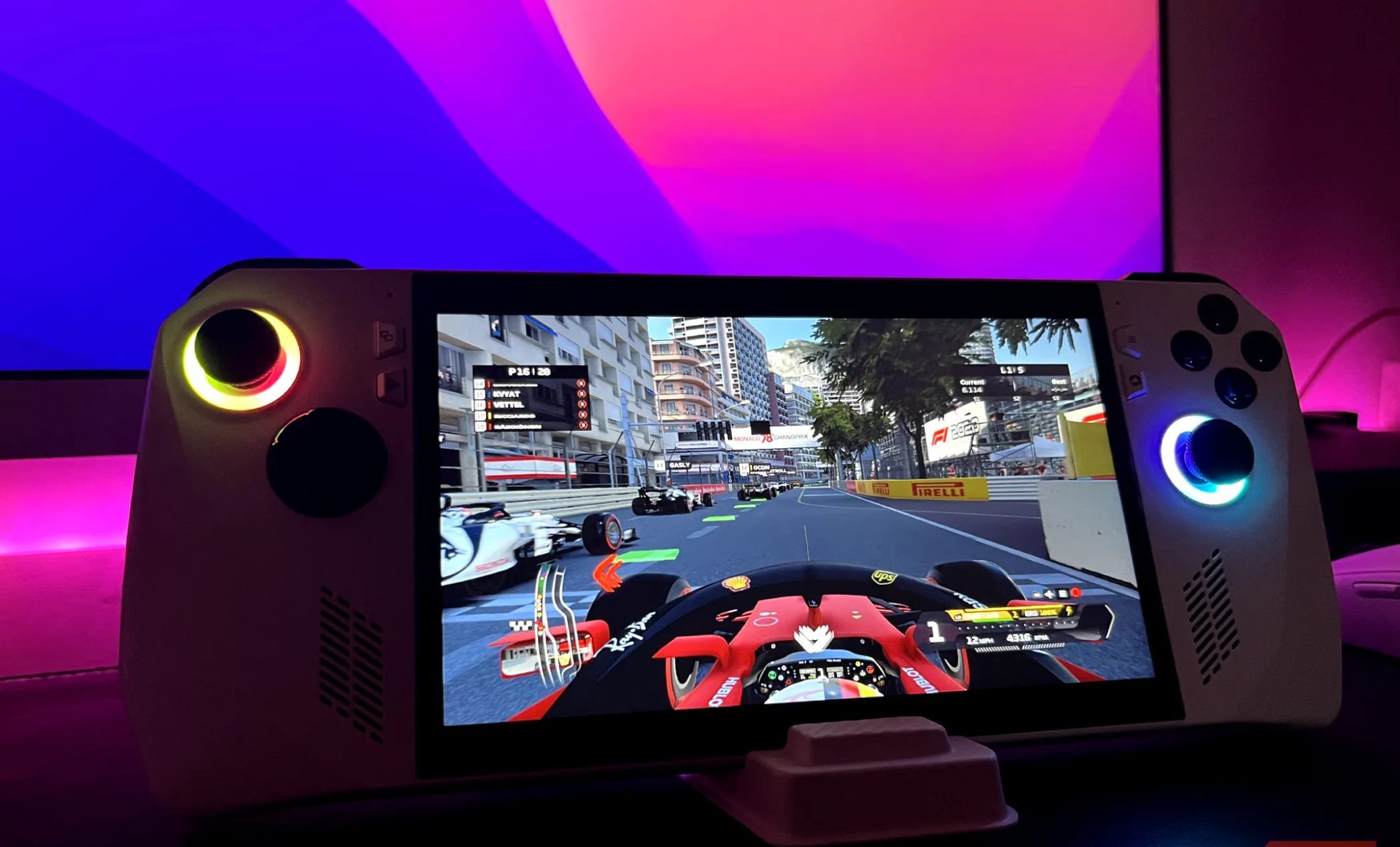 ASUS ROG Ally on a stand with a monitor in the background