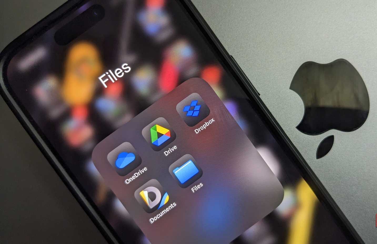 مجلد تطبيقات التخزين السحابي على iPhone فوق جهاز MacBook بشعار Apple