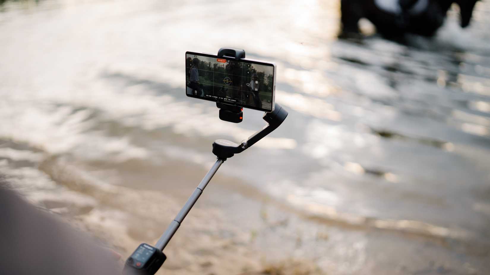 Hohem iSteady V3 Ultra being held with phone over the water