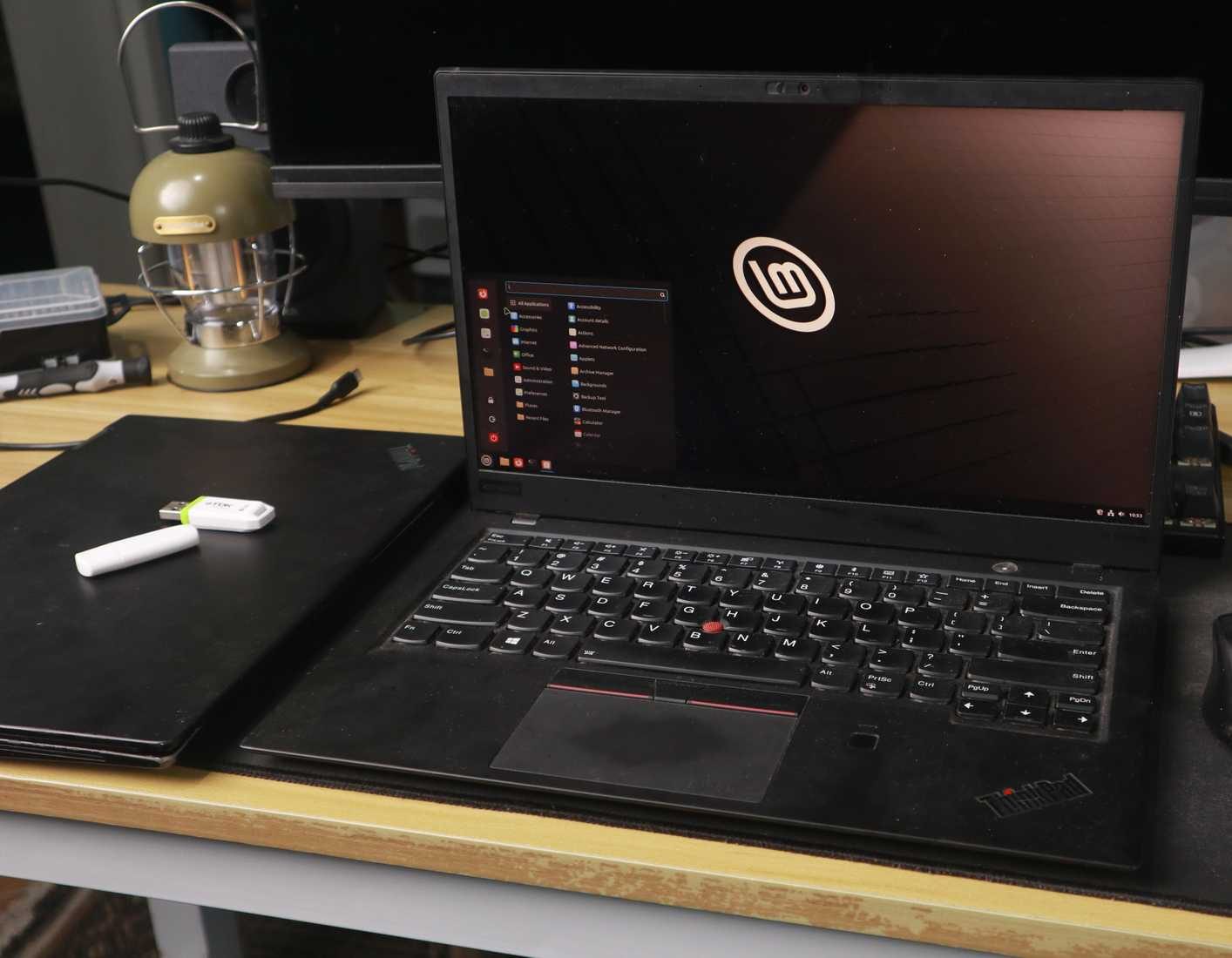 Linux Mint desktop on a ThinkPad laptop, with a mouse and USB stick nearby