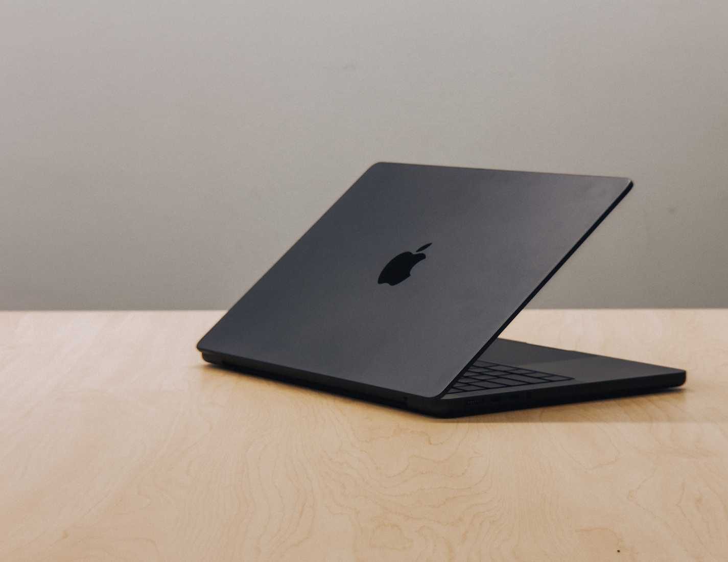 M4 MacBook Pro مع شاشة مائلة للأسفل على طاولة خشبية