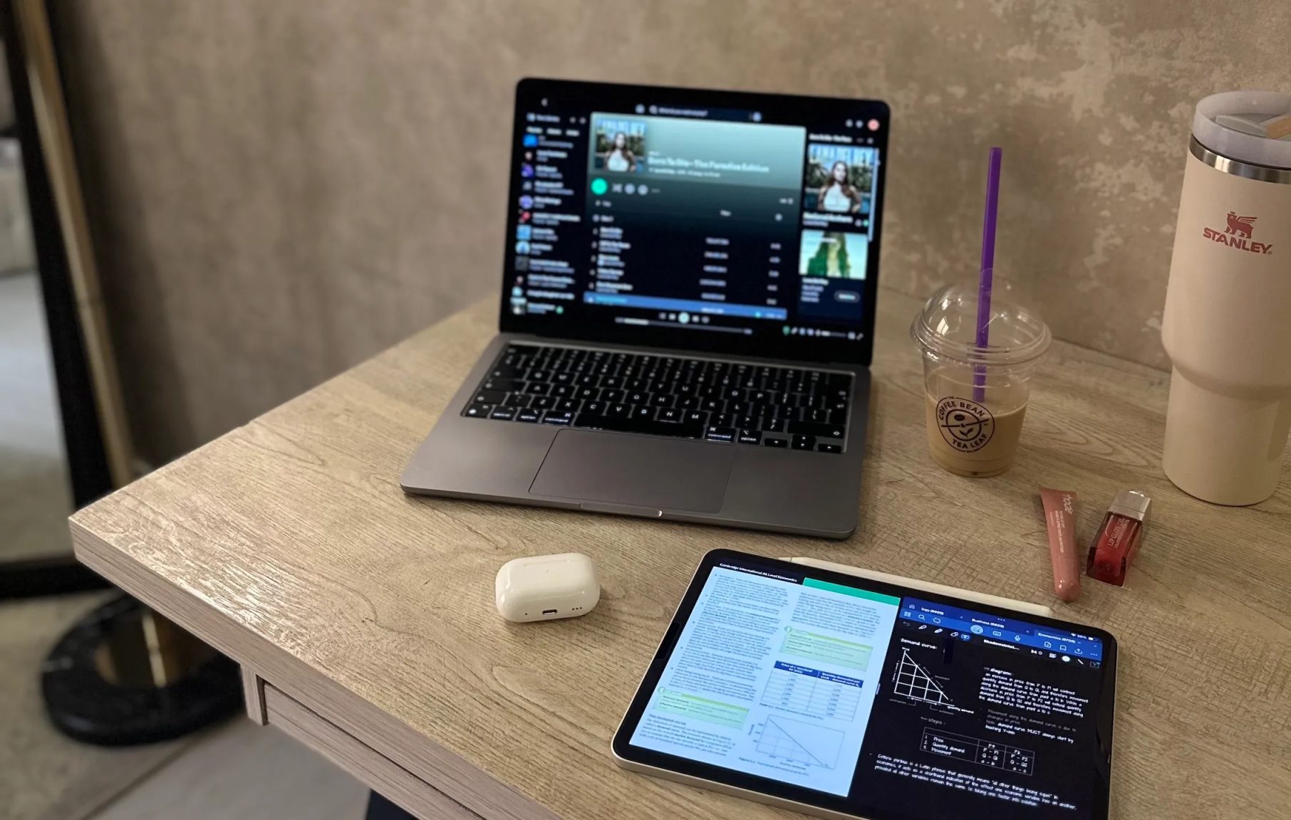 Mac and iPad on a desk next to a Stanley and coffee cup