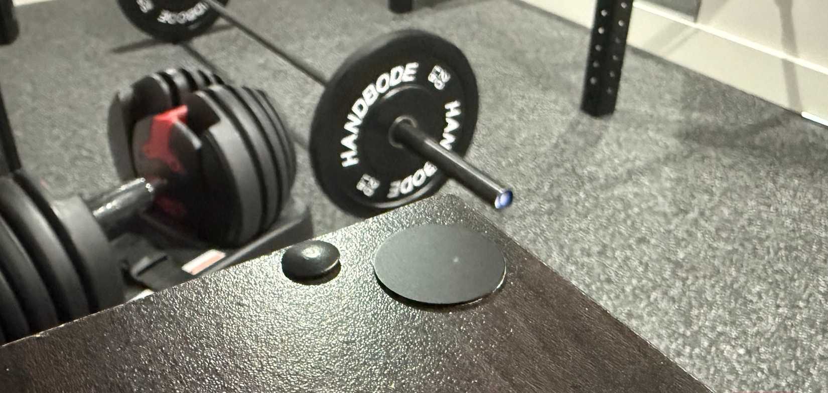 علامة NFC سوداء في صالة الألعاب الرياضية المنزلية مع الأوزان في الخلفية